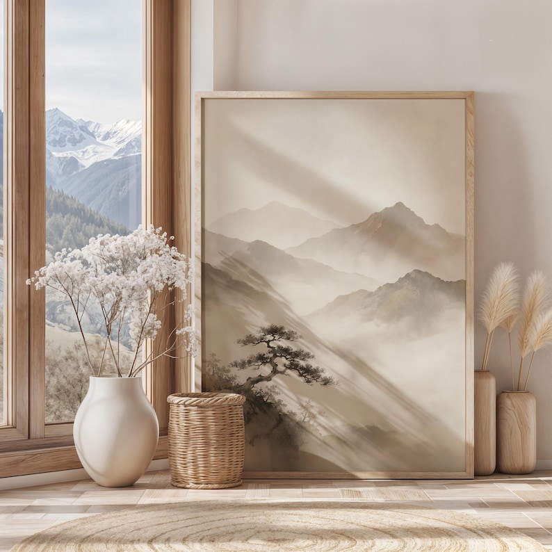 May include: A framed vertical wall art print featuring a monochromatic landscape of misty mountains and a lone pine tree in shades of beige and cream. The artwork is displayed in a light wood frame, positioned next to a white vase with dried flowers.