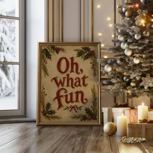 May include: A rectangular framed print featuring the red text Oh, what fun in a decorative script font. The print is decorated with green holly leaves and red berries in the corners. The frame is gold and sits on a wooden floor.