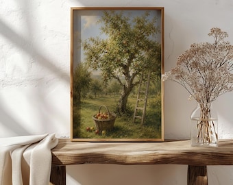 May include: A framed wall art print depicting an orchard scene with a large apple tree, a wooden ladder leaning against the trunk, and a woven basket filled with red apples on the grass. The artwork features soft green, brown, and red tones.