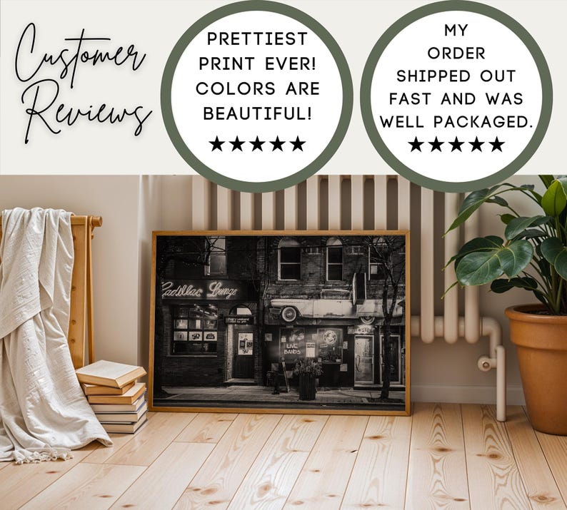 May include: A framed black and white photograph of a vintage building with the text "Cadillac Lounge" in neon. The image is displayed on a wooden floor, with customer reviews in the background.
