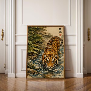 Puede incluir: Una impresi&oacute;n art&iacute;stica enmarcada que presenta un tigre en un arroyo. El tigre tiene rayas naranjas y negras y camina hacia el espectador. La obra de arte tiene una est&eacute;tica vintage con texto japon&eacute;s en la esquina superior izquierda y est&aacute; rodeada por un marco de madera.