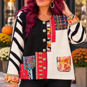 May include: A long-sleeve button-up jacket featuring a patchwork design with black, white, and red panels. The garment includes black and white striped sleeves, a solid black side, a solid white side, and colorful patterned pockets and trim.