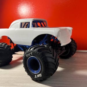 Op de afbeelding: Wit monstertruck-model met een Chevrolet-carrosserie uit de jaren 1950, zwarte banden met BKT-lettering en blauwe accenten.