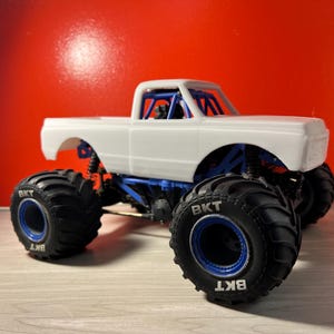May include: White monster truck body with a black and blue tire with the text "BKT" on the side.