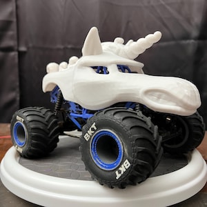 May include: White monster truck with a unicorn horn and blue wheels. The wheels have the text "BKT" on them.