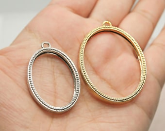 May include: Two oval-shaped metal picture frames with a beaded edge. The frame on the left is silver and the frame on the right is gold.
