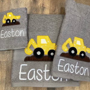 May include: A set of three gray towels with embroidered yellow construction trucks and the name Easton on each towel.