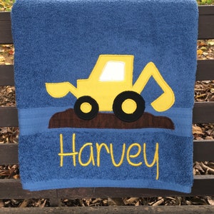 May include: Blue towel with a yellow embroidered excavator and the name Harvey in yellow embroidery.