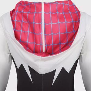 Puede incluir: Mono con capucha blanco con mangas largas. El interior de la capucha presenta un dise&ntilde;o de telara&ntilde;a roja y azul. El mono tiene un torso negro con detalles blancos en zigzag.