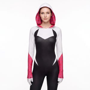 May include: A long-sleeved hooded bodysuit featuring a black torso, white upper chest and sleeves, and pink web-patterned accents on the hood interior and lower sleeves. The garment has a fitted silhouette with a pointed white neckline detail.