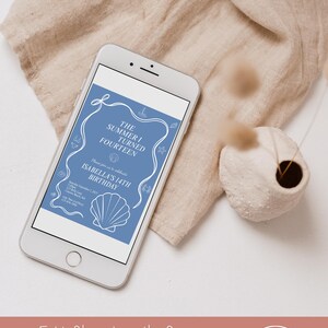 May include: A smartphone displays a blue invitation with white text and nautical illustrations for Isabella's 14th birthday. The phone rests on a beige cloth, with a small vase and dried plant nearby. Text at the bottom reads, "Edit files directly from your phone or mobile device!"