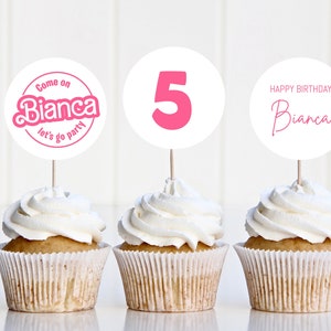 May include: Three cupcakes with white frosting and pink and white cupcake toppers. The toppers say "Come on Bianca let's go party", "5", and "Happy Birthday Bianca".