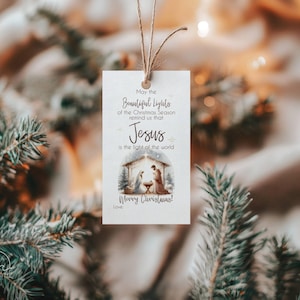 Peut inclure: Une étiquette cadeau rectangulaire de Noël avec une illustration de la Nativité. Le texte sur l'étiquette dit : "Que les belles lumières de la saison de Noël nous rappellent que Jésus est la lumière du monde. Joyeux Noël!"
