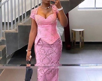 Puede incluir: Una mujer con un vestido rosa con un corpiño ajustado y una falda fluida. El vestido está adornado con lentejuelas y cuentas. Lleva un turbante rosa y un collar de perlas.