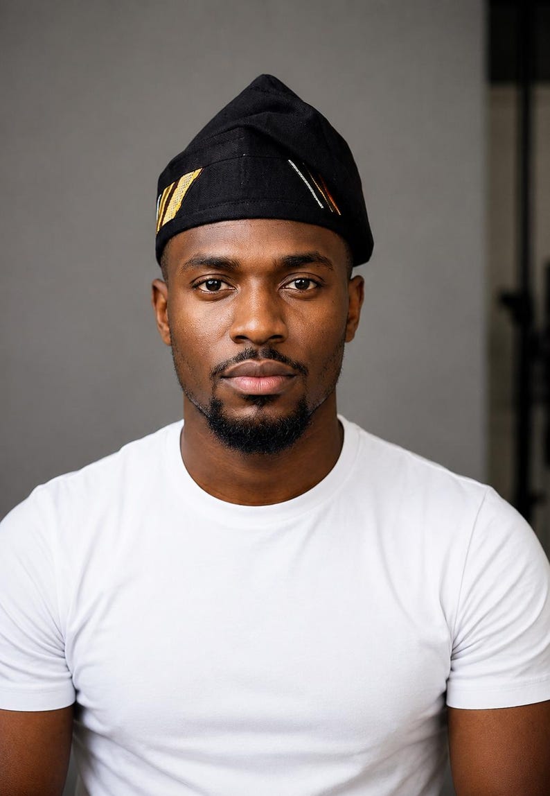 Puede incluir: Un gorro negro con corona puntiaguda y rayas decorativas bordadas en dorado y blanco en el lateral. El gorro se lleva sobre la cabeza y presenta un dise&ntilde;o estructurado y plegado con una base de tela negra s&oacute;lida y detalles geom&eacute;tricos.
