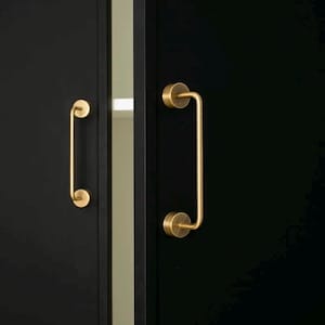 Puede incluir: Primer plano de dos puertas de armario negras con tiradores dorados y curvos. Los tiradores son cilíndricos en los extremos y tienen una barra vertical redondeada. Las puertas están una al lado de la otra, con un espacio estrecho y claro entre ellas.