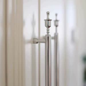 Può includere: Primo piano di due maniglie per porte argentate lucide. Ogni maniglia ha un corpo cilindrico con una parte superiore decorativa e un braccio curvo per l'impugnatura. Le maniglie sono montate su una porta bianca, creando un'estetica moderna.