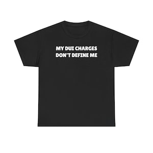 Könnte beinhalten: Ein schwarzes T-Shirt mit kurzen Ärmeln und dem weißen Text MY DUI CHARGES DON'T DEFINE ME, der in einer fetten, serifenlosen Schrift mittig auf der Brust aufgedruckt ist. Das Kleidungsstück hat einen Rundhalsausschnitt und einen geraden Schnitt.