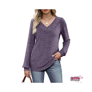 May include: A long-sleeved, purple V-neck sweater with a ribbed texture. The sweater has a relaxed fit and a curved hemline. The sleeves are long and slightly flared at the cuffs. The neckline has a decorative cross-over design.