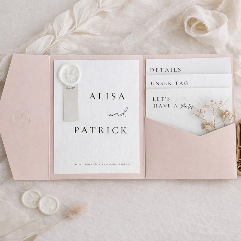 May include: A pale pink tri-fold wedding invitation suite featuring a white card with the text Alisa und Patrick, a wax seal, and three insert cards labeled Details, Unser Tag, and Let's Have a Party, accented with a small dried flower sprig.