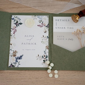 May include: An open olive green wedding invitation suite with floral accents. The invitation features the names "ALISA and PATRICK" and the date "19. August 2026". A wax seal, a stamp, and additional cards are included.