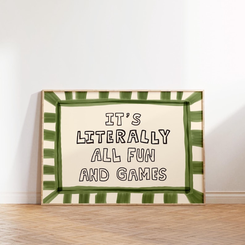 Pu&ograve; includere: Una stampa artistica da parete rettangolare con sfondo color crema e il testo nero IT'S LITERALLY ALL FUN AND GAMES. La stampa &egrave; incorniciata da un ampio bordo in stile dipinto a mano composto da strisce alternate verde scuro e crema.