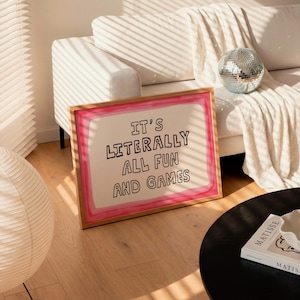 Pu&ograve; includere: Un'opera d'arte da parete rettangolare incorniciata con sfondo bianco, un bordo dipinto in rosa e il testo nero "IT'S LITERALLY ALL FUN AND GAMES" centrato al centro. La cornice &egrave; in legno chiaro e poggia sul pavimento.