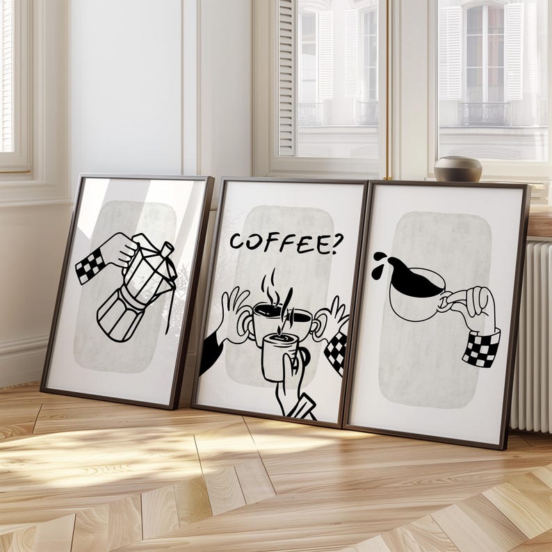 May include: Set of three framed art prints with black and white coffee-themed illustrations. One shows a coffee maker, another asks "COFFEE?" and the third depicts coffee pouring into a cup. Each image features hands with checkered sleeves.