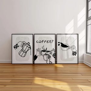 May include: Set of three framed black and white coffee-themed art prints. Each print features a different coffee-related illustration: a coffee maker, the word "COFFEE?" with coffee cups, and coffee pouring into a cup. The hands in the illustrations have checkered sleeves.