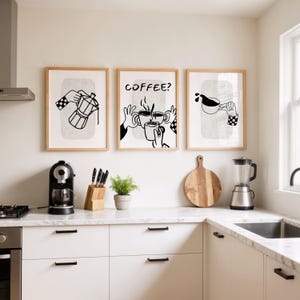 May include: Three framed art prints with coffee-themed illustrations. The prints feature black and white line drawings of a coffee maker, hands holding mugs, and pouring coffee. The text "COFFEE?" is in one print. The prints are in a kitchen setting.