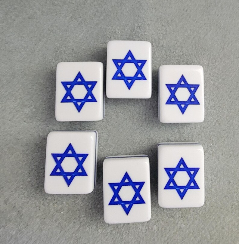 May include: Six white rectangular tiles with a blue Star of David design. The tiles are arranged in a circular pattern against a gray background. The Star of David is a six-pointed star, a symbol of Judaism.