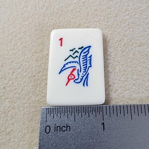 May include: A white tile with a blue and red bird design and the number "1" in the top left corner. The tile is approximately 1 inch wide.