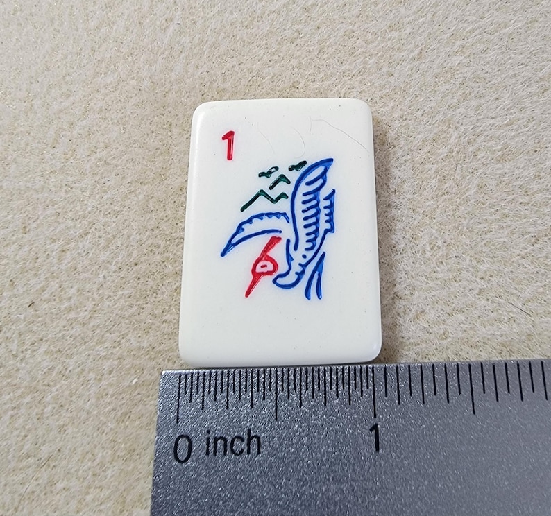 May include: A white tile with a blue and red bird design and the number "1" in the top left corner. The tile is approximately 1 inch wide.