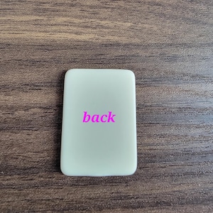 May include: A white rectangular sign with the word "back" printed in pink.