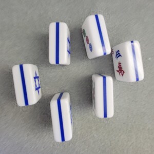 May include: Six white Mahjong tiles with blue vertical stripes and various symbols and characters. Some tiles feature a blue Star of David. The tiles are arranged on a gray surface.