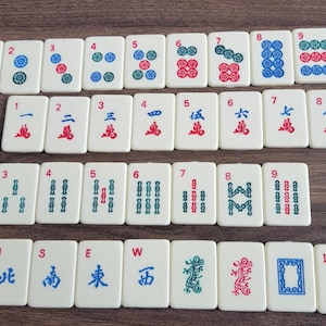 May include: A set of 36 mahjong tiles with white backgrounds and red, blue, and green symbols. The tiles are numbered 1 through 9 and include wind, dragon, and bamboo symbols.