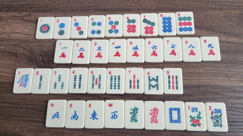 May include: A set of 36 mahjong tiles with white backgrounds and red, blue, and green symbols. The tiles are numbered 1 through 9 and include wind, dragon, and bamboo symbols.