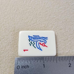 May include: A white ceramic tile with a blue and red bird design. The tile has a number "1" printed on it.