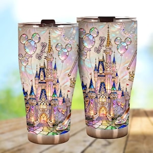 Puede incluir: Dos vasos de viaje de acero inoxidable con un diseño de castillo de cuento de hadas. El diseño incluye un castillo, globos de Mickey Mouse, una varita mágica y un zapato de cristal. El nombre "Sophia" está escrito en los vasos.