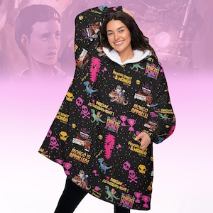 May include: A black hooded blanket with a white interior, featuring a repeating pattern of cartoon dinosaurs, skulls, trophies, and text. The text includes "Princess Donut & Mongo" and "New Achievement!"