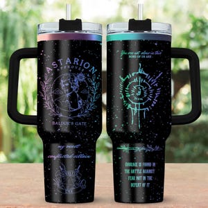 Può includere: Bicchiere termico nero con manico e cannuccia. Un lato presenta un disegno con il testo "Astarion Approves" e "Baldur's Gate". L'altro lato ha il testo "You are not alone in this, none of us are". Entrambi i lati hanno testo e grafica aggiuntivi.