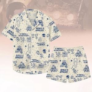 Może przedstawiać: Kremowy zestaw piżamowy z koszulą zapinaną na guziki i szortami. Zestaw posiada powtarzający się wzór postaci z kreskówek, czaszek, trofeów i tekstu w kolorze niebieskim. Koszula ma krótkie rękawy i kołnierzyk z klapami. Szorty mają elastyczną talię.