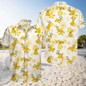 Może przedstawiać: Biała koszula zapinana na guziki z powtarzającym się wzorem Pluto, psa z kreskówek Disneya, w różnych pozach. Koszula ma również żółte kwiatowe akcenty. Koszula jest z krótkim rękawem.