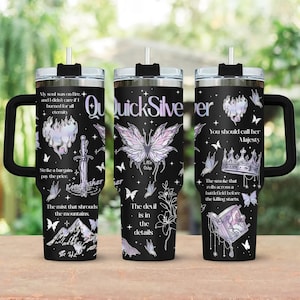 May include: Black travel tumbler with a handle, featuring a butterfly and floral design with the text "QuickSilver". The tumbler has a black lid and straw. Additional text includes phrases like "My soul was on fire" and "The devil is in the details".