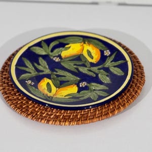 May include: A blue and yellow ceramic plate with a lemon design. The plate is on a woven brown placemat.