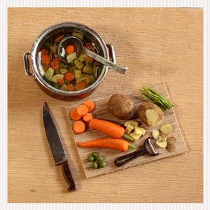 Könnte beinhalten: Draufsicht auf eine Kochszene mit einem Topf Gemüsesuppe, einem Messer und einem Schneidebrett mit Karotten, Kartoffeln und grünen Bohnen. Der Text "Online class vegetable soup" befindet sich links.
