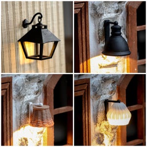 Puede incluir: Cuatro lámparas de pared en miniatura con diferentes diseños. Las lámparas son negras y emiten una cálida luz amarilla. Una tiene forma geométrica, otra de cúpula, una tercera con pantalla de mimbre y la última con pantalla de cristal acanalado.