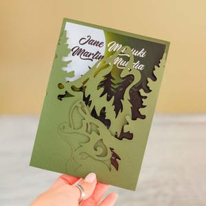 Könnte beinhalten: Grüne, lasergeschnittene Hochzeitseinladung mit einem Blattdesign. Die Einladung trägt die Namen "Jane Martin" und "Miki Murda".
