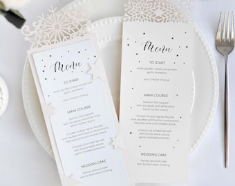Op de afbeelding: Twee witte menukaarten voor een bruiloft met sneeuwvlokkenuitsnijdingen. Het menu bevat een keuze uit soep, zalmfilet, kipfilet en rundvlees, evenals een vanille-amandelcake met botercrème.
