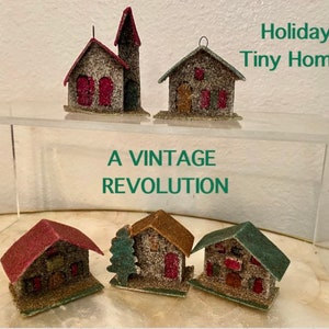 May include: A collection of five vintage, miniature, felt Christmas houses. The houses are decorated with glitter and have red, green, and brown accents. The houses are displayed on a clear acrylic shelf with the text "Holiday Tiny Homes" and "A Vintage Revolution" printed below.